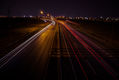 trail of cars at night from the top of a bridge