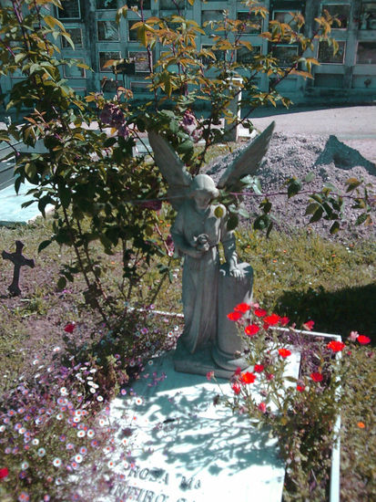 arbol, estatua y flores rojas 