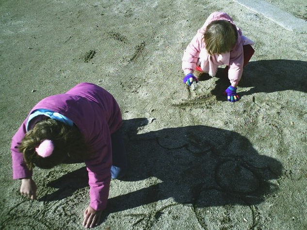 Niños dibujando en la arena 