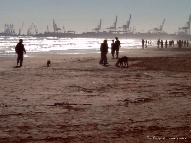 Paseantes en la playa y el puerto al fondo, (Walkers on the beach and the port at the background)